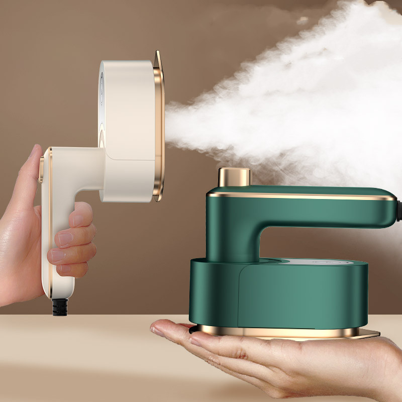 The steam iron held upright releasing steam (left, shown in beige) and the green version resting on a palm (right)